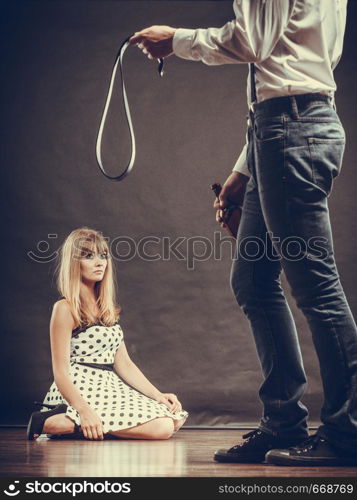 Alcoholism and violence problem. Man alcoholic holding bottle beating his scared wife with belt. Woman is victim of domestic abuse.