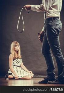 Alcoholism and violence problem. Man alcoholic holding bottle beating his scared wife with belt. Woman is victim of domestic abuse.