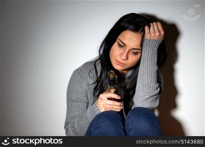 alcoholism, depression and people concept - unhappy drunk crying woman with bottle of alcohol. unhappy drunk crying woman with bottle of alcohol