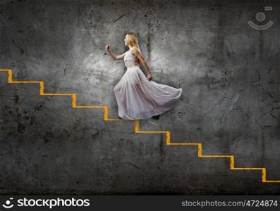 Alice in wonderland. Young woman in white long dress stepping up the staircase