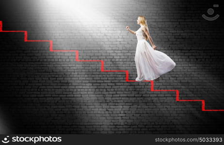 Alice in wonderland. Young woman in white long dress stepping up the staircase