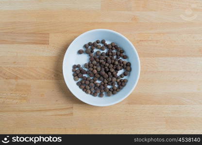 Allspice in a bowl on wood.. Allspice in a bowl on wood