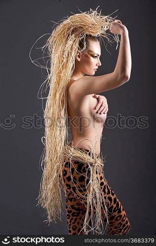 alluring and sexy girl with raffia hair and a ethnic costume in a shot over dark with creative make up