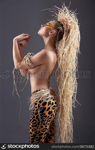 alluring and sexy woman with raffia hair and a ethnic costume in a shot over dark with creative make up