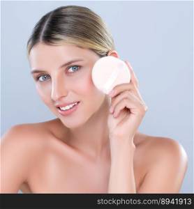 Alluring beautiful female model applying powder puff for facial makeup concept. Portrait of flawless perfect cosmetic skin woman put powder foundation on her face in isolated background.. Alluring beautiful female model applying powder puff for facial makeup concept.