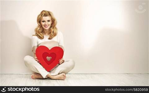 Alluring blonde girl holding red valentine&rsquo;s heart