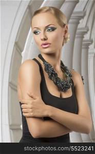 alluring blonde girl with fashion look, elegant hair-style, nice blue make-up, dark dress and creative big beads necklace