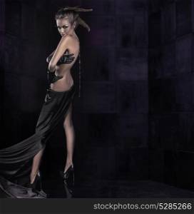 Alluring, nude woman posing in a dark place