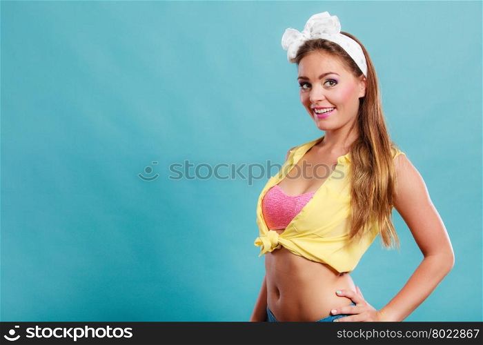 Alluring seductive pretty pin up girl with hairband bow. Attractive gorgeous young retro woman posing in studio on blue background.