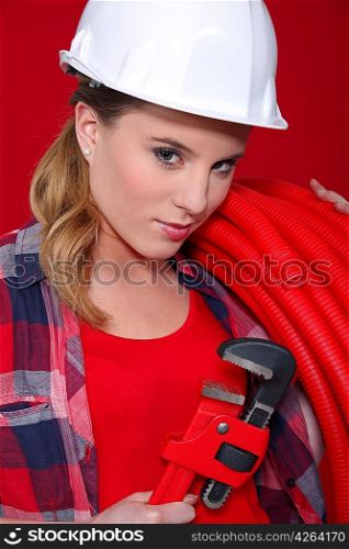 Alluring woman holding corrugated tubing and a pipe wrench