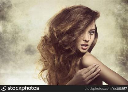 alluring young girl posing in fashion shoot with naked shoulder and creative bushy hairdo