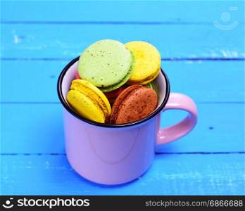 Almond biscuit macaron in a mug on a blue wooden background, top view