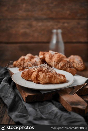 Almond croissant with custard filling on wood background.