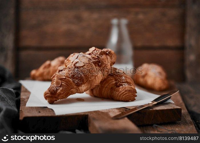 Almond croissant with custard filling on wood background.