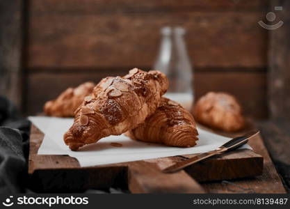 Almond croissant with custard filling on wood background.