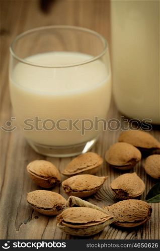 Almond milk with almonds on a wooden table and focus with shallow depth of field