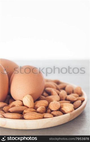 Almond nuts and eggs on wooden plate, stock photo
