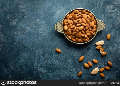 Almond nuts on dark background directly above copy space flat lay