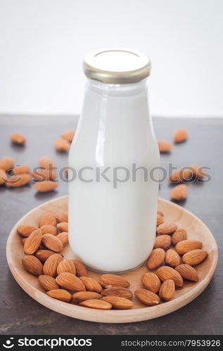 Almond nuts on wooden plate with milk, stock photo