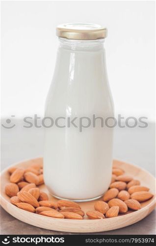 Almond nuts on wooden plate with milk, stock photo