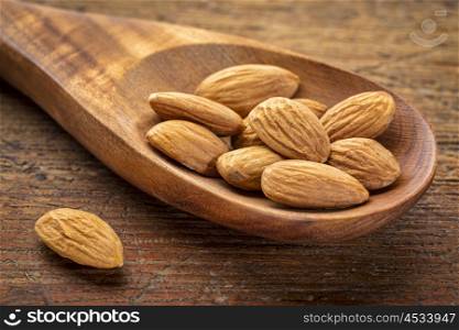 almond nuts on wooden spoon against grunge wood background