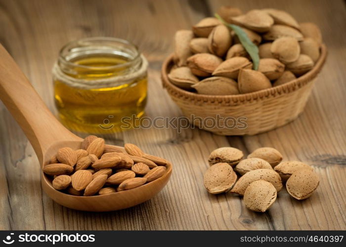 Almond oil and almonds on an old wooden background, selective focus