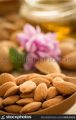 Almond oil and almonds on an old wooden background, selective focus