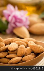 Almond oil and almonds on an old wooden background, selective focus