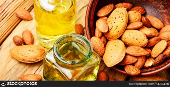 Almond oil in bottle and nuts. Almond oil in glass bottle and almonds on retro table