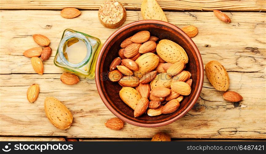 Almond oil in bottle and nuts. Almond oil in glass bottle and almonds on retro table.Almond massage oil