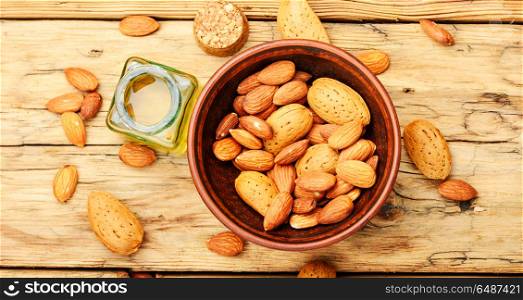 Almond oil in bottle and nuts. Almond oil in glass bottle and almonds on retro table.Almond massage oil