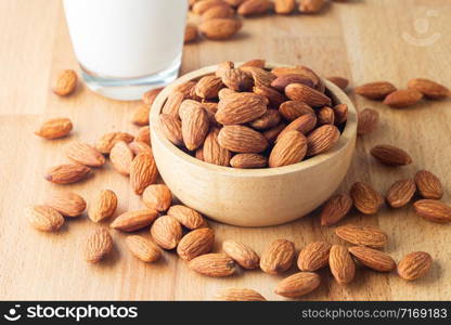 Almond seeds in a bowl wood and milk glass on table wooden