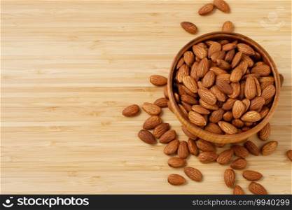 Almonds in brown wooden bowl on old wooden table background