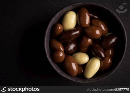 almonds in white, dark, milk chocolate in a bowl on stone board