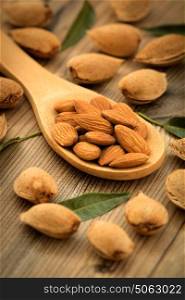 Almonds on brown wooden background with the focus in the spoon