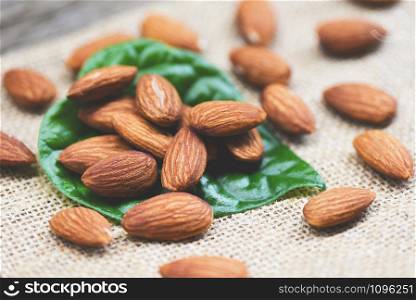 Almonds on green leaf / Close up almond nuts natural protein food and for snack on sack background , selective focus