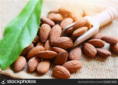 Almonds on wooden scoop and sack background top view on the table, Close up roasted almond nuts natural protein food and for snack