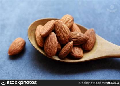 Almonds on wooden spoon and dark background top view on the table, Close up roasted almond nuts natural protein food and for snack