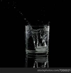 almost black and white of a splash from a falling ice cube in glass of water. splash from a falling ice cube in glass of water
