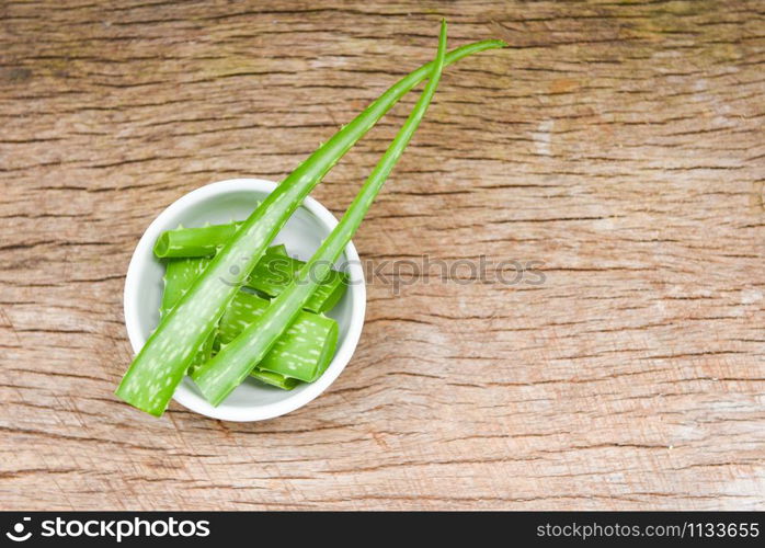 aloe vera plant slice in bowl on rustic wood background / close up of fresh aloe vera leaf with gel natural herbs and herbal medicines
