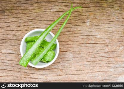 aloe vera plant slice in bowl on rustic wood background / close up of fresh aloe vera leaf with gel natural herbs and herbal medicines