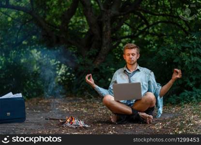 Alone businessman with laptop at the fireplace on desert island. Business risk, collapse or bankruptcy concept. Alone businessman with laptop at fireplace, island
