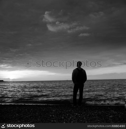 alone man looking at the sunset on a beach