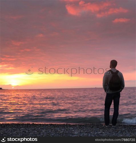 alone man looking at the sunset on a beach