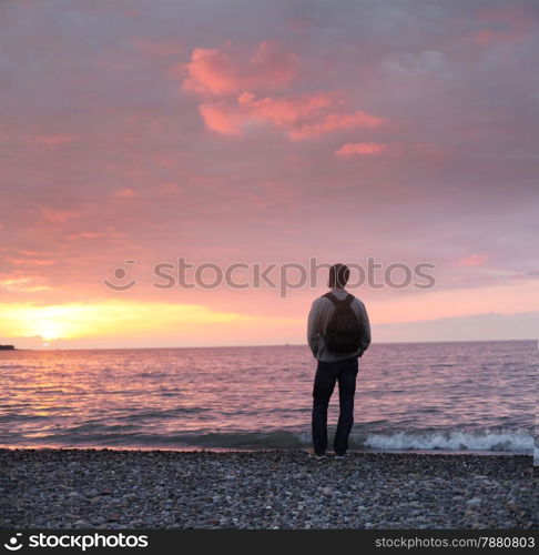 alone man looking at the sunset on a beach