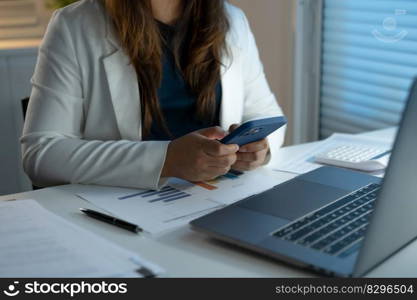 Alone Working Late at Night. Asian business woman at workplace in office late night work at a desk in a dark office working on a laptop late in the evening.