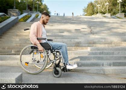 Alone young man in wheelchair at the stairs, helpless and handicap problem. Paralyzed people and disability difficulties, handicap overcoming. Disabled male person walking in park. Alone man in wheelchair at the stairs, disability