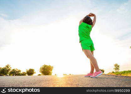 Along the road in the hillside area at the time of the sun set woman is exercising by running.