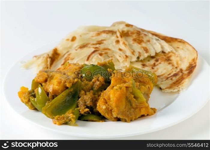 Aloo capsicum, potato and bell pepper vegetarian curry, served with paratha fried flatbread in the traditional way, side view