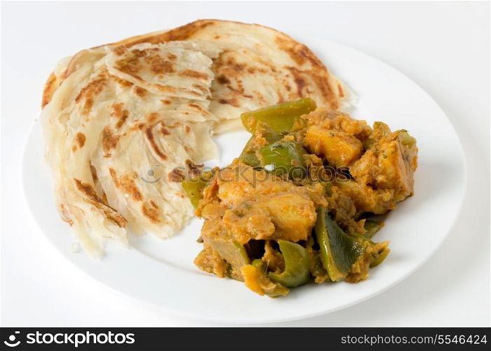 Aloo capsicum, potato and bell pepper vegetarian curry, served with paratha fried flatbread in the traditional way.